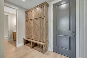 Mudroom featuring light wood finished floors and baseboards