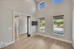 Spare room with light wood finished floors and a towering ceiling