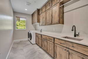 Washroom featuring cabinet space, light marble finish floors, separate washer and dryer, and recessed lighting