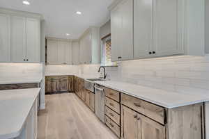 Kitchen featuring dishwasher, light wood finished floors, tasteful backsplash, recessed lighting, and light countertops