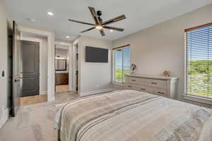 Bedroom with light colored carpet, recessed lighting, ensuite bathroom, and ceiling fan