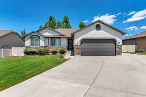 Single story home with stucco siding, concrete driveway, an attached garage, and a gate