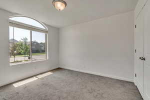 Carpeted spare room with baseboards and vaulted ceiling