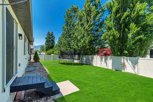 Fenced backyard featuring a trampoline