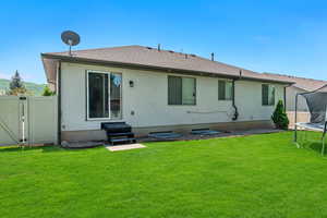 Back of house featuring a trampoline, roof with shingles, a gate, and entry steps