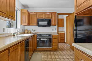 Kitchen with black appliances, light countertops, and brown cabinetry