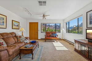 Living room featuring carpet, baseboard heating, ceiling fan, and a mountain view