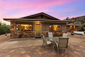 Back of house with a patio, outdoor dining area, and stone siding