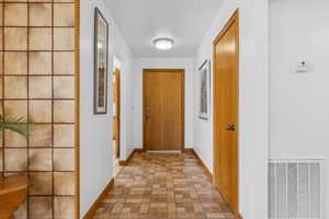 Corridor featuring brick patterned floors and baseboards