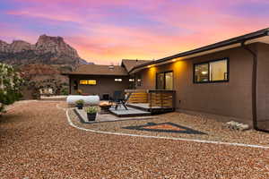 Back of property featuring a deck with mountain view, stucco siding, an outdoor hangout area, and a patio area