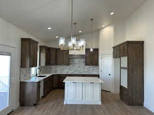 Kitchen with a kitchen island, a chandelier, decorative light fixtures, lofted ceiling, and dark brown cabinets