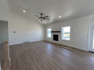 Unfurnished living room featuring a fireplace, light wood-type flooring, ceiling fan, recessed lighting, and high vaulted ceiling