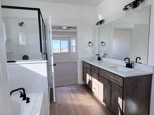 Bathroom with double vanity, a garden tub, light wood finished floors, a shower stall, and a ceiling fan