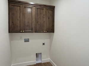 Washroom featuring dark wood-type flooring, hookup for a washing machine, cabinet space, and hookup for an electric dryer