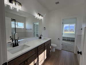 Bathroom with dark wood finished floors, double vanity, a stall shower, and a bath