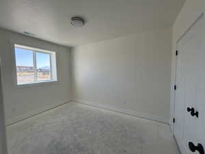 Unfurnished bedroom with baseboards and unfinished concrete floors