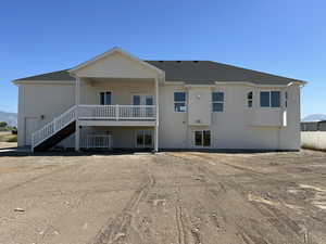 Back of property featuring a mountain view, stairway, roof with shingles, and a patio
