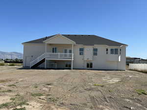Rear view of house featuring a patio area, a shingled roof, stairs, and a balcony