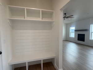 Mudroom featuring a large fireplace, wood finished floors, and a ceiling fan
