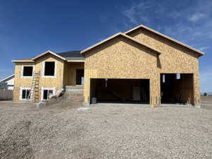 Unfinished property with an attached garage, gravel driveway, and stucco siding