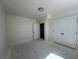 Unfurnished bedroom featuring a closet and concrete floors