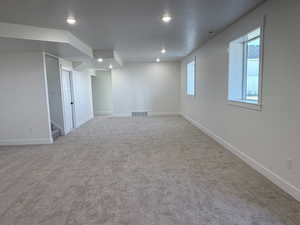 Basement with light colored carpet, stairs, and recessed lighting