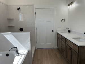 Full bathroom featuring a tile shower, a garden tub, light wood-type flooring, and double vanity