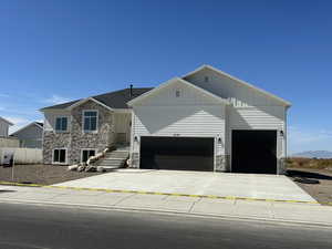 View of front facade featuring stone siding, board and batten siding, concrete driveway, and an attached garage