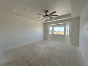 Empty room with a raised ceiling and a ceiling fan