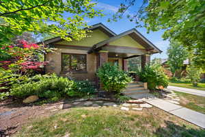 View of front of home featuring covered porch, brick siding, and a front yard