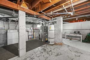 Unfinished basement featuring water heater, washer / clothes dryer, and heating unit