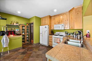 Kitchen with white appliances, tile countertops, stone finish flooring, and recessed lighting