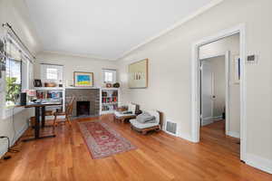 Living area featuring wood finished floors, a fireplace, and ornamental molding