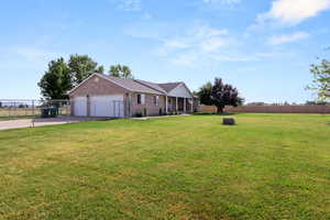 Single story home featuring concrete driveway, a 3-car garage, brick siding, and a fenced yard