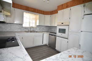 Kitchen featuring white appliances backsplash, light countertops, and white cabinets, wall oven, dishwasher and sink