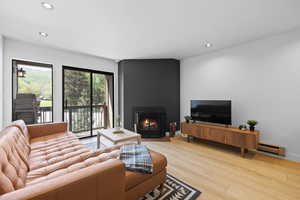 Living room with a large fireplace, recessed lighting, and light wood-style flooring