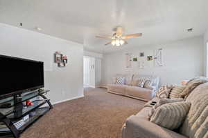 Living area featuring a ceiling fan and carpet