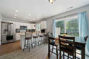 Kitchen with appliances with stainless steel finishes, white cabinets, recessed lighting, a peninsula, and a breakfast bar area