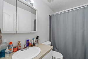 Full bathroom with vanity, a textured ceiling, and a shower with curtain