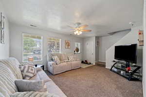 Carpeted living room with a textured ceiling and a ceiling fan