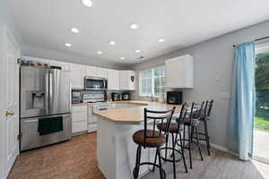 Kitchen with appliances with stainless steel finishes, a peninsula, recessed lighting, plenty of natural light, and white cabinets