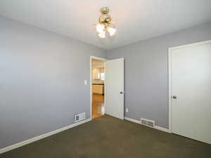 Unfurnished bedroom with dark colored carpet and baseboards