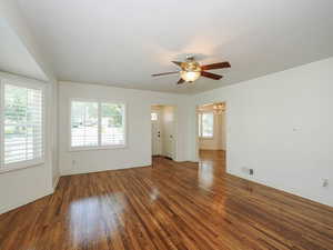 Unfurnished room featuring a chandelier, a ceiling fan, and wood finished floors