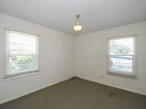 Spare room featuring plenty of natural light and dark carpet