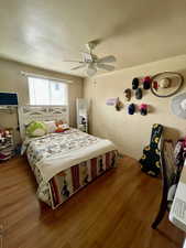 Bedroom with wood finished floors, a textured ceiling, and ceiling fan