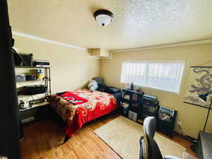 Bedroom featuring wood finished floors, ornamental molding, and a textured ceiling