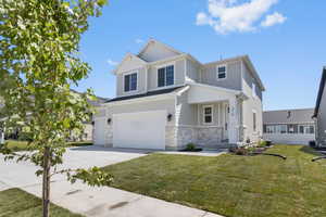 View of front of house featuring stone siding, a garage, concrete driveway, and a front yard