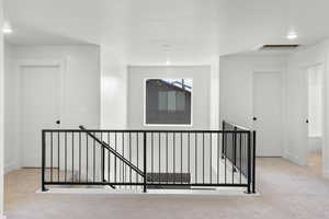 Hall with an upstairs landing and carpet flooring