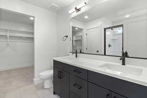Bathroom with a spacious closet, double vanity, a shower stall, tile patterned floors, and recessed lighting