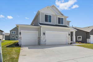 Craftsman-style home with concrete driveway, a front yard, stone siding, and an attached garage